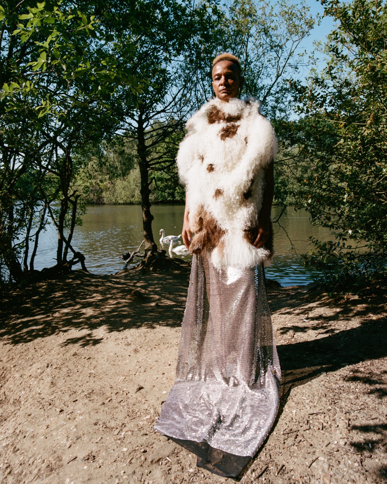 A model wearing a large garment from Ponte brand stands tall in front of a lake surrounded by trees.