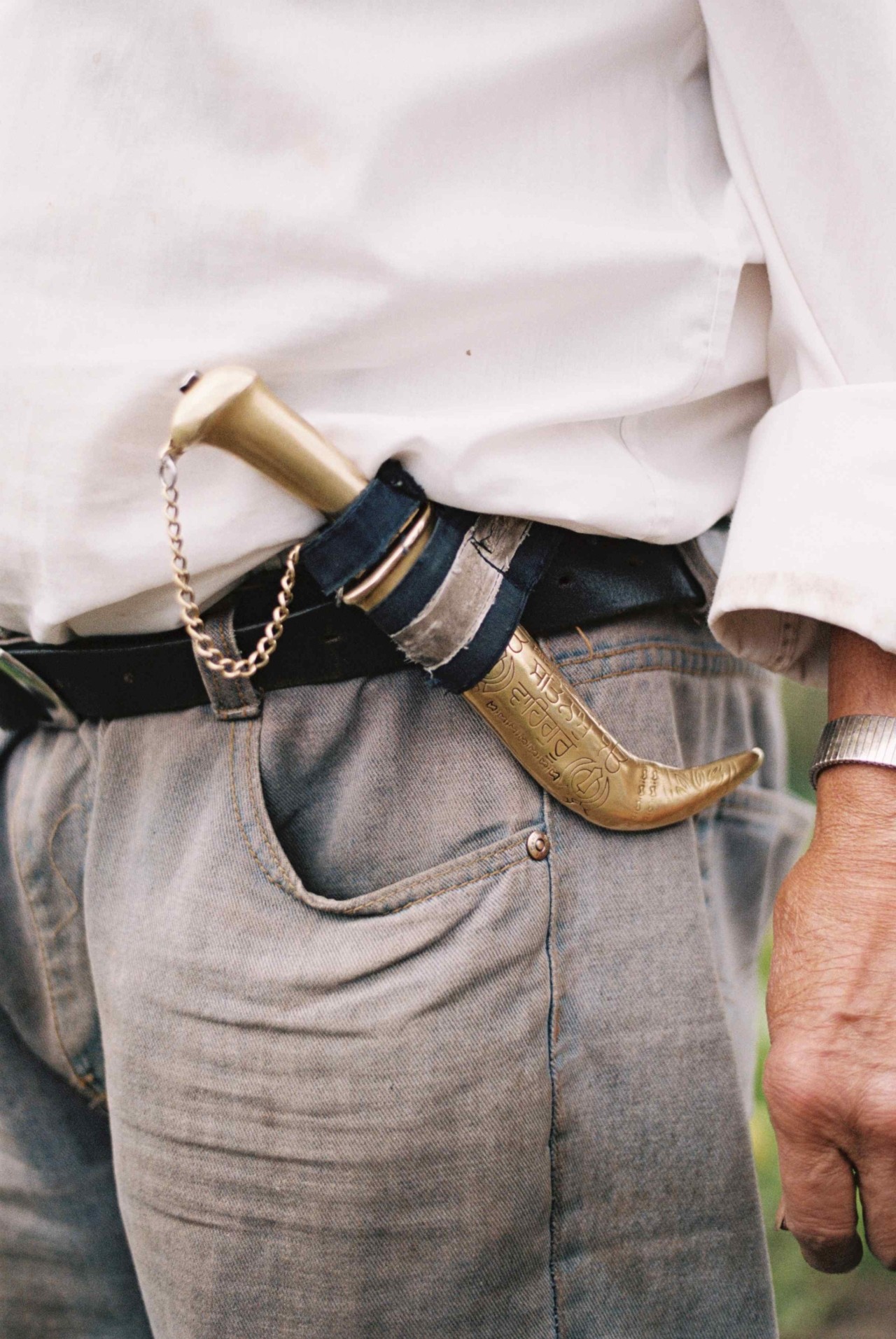 The belt of a farmer holds a small golden tool.