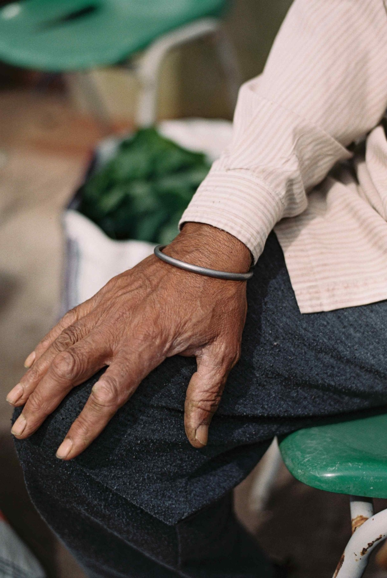 The hand of a Punjabi Sikh farmer rests on their leg.