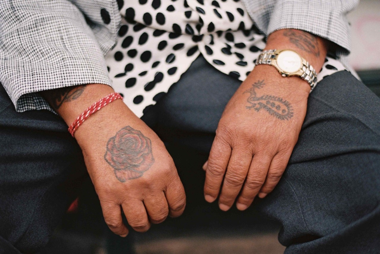 The hands of a Punjabi Sikh farmer rests on their legs.