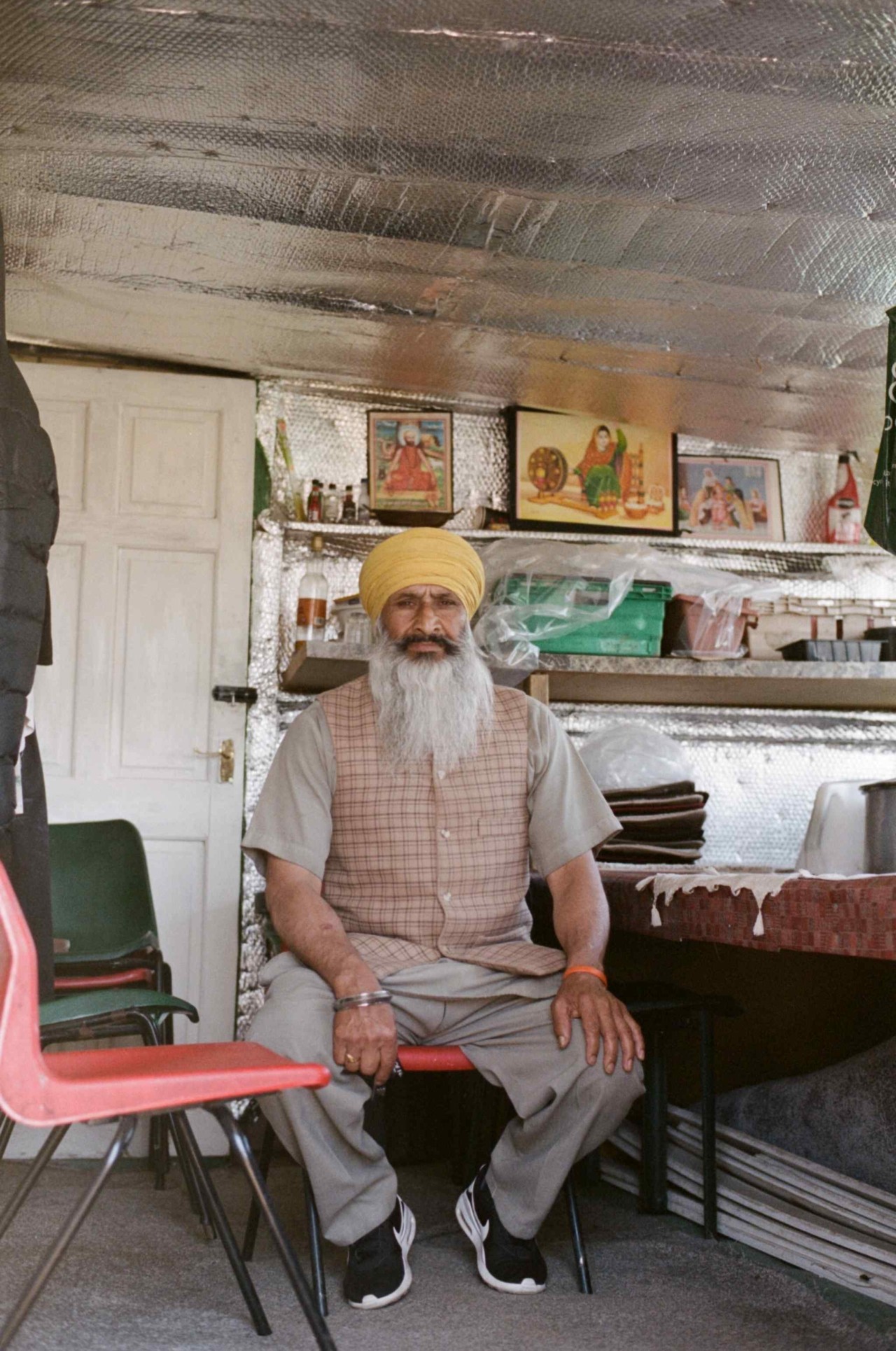 A Punjabi Sikh farmer sits in a chair inside a home.