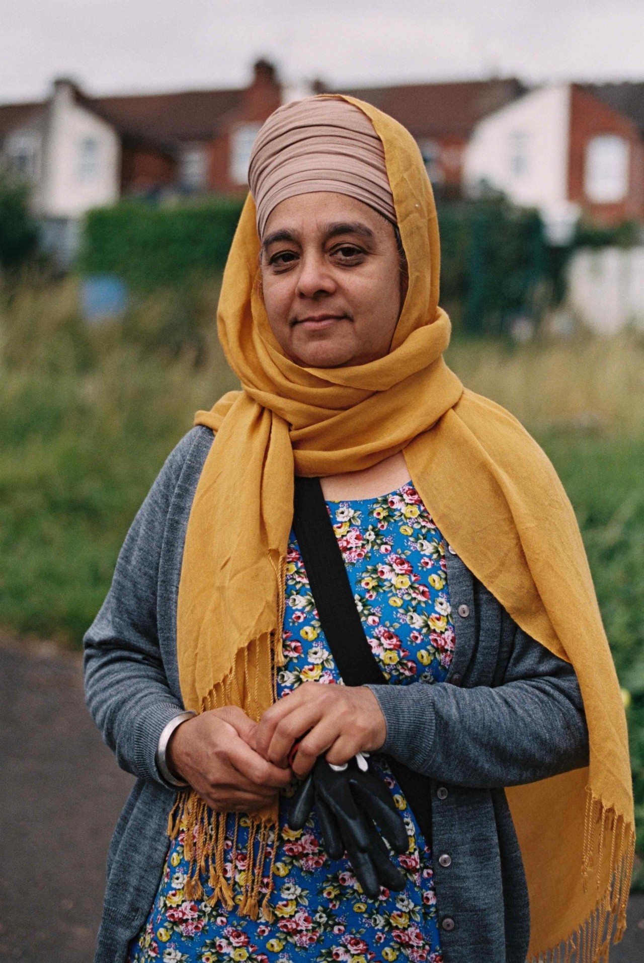 A Punjabi Sikh farmer wearing bright colored clothes stands in the road.