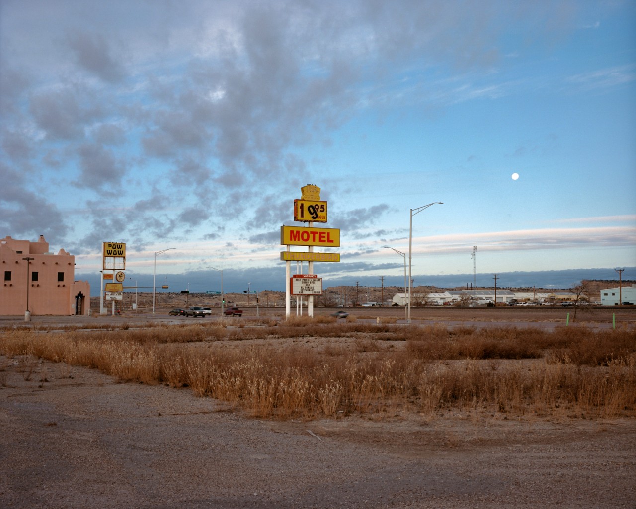 A motel sign stands tall among dry grass along Route 66.