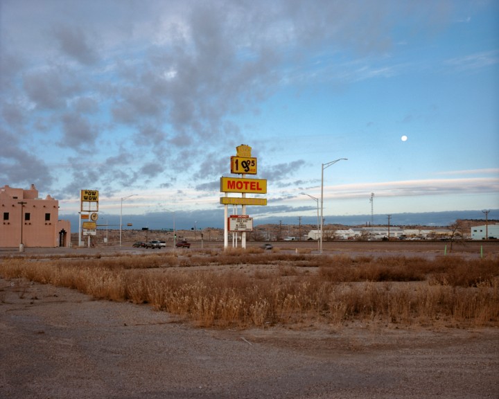 A motel sign stands tall among dry grass along Route 66.
