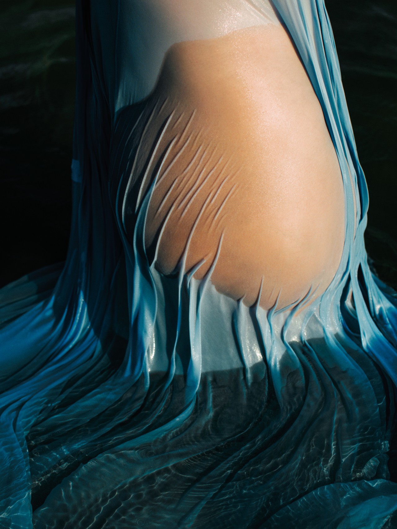 A blue dress is soaked to transparency, sticking to the midriff of the person wearing it.