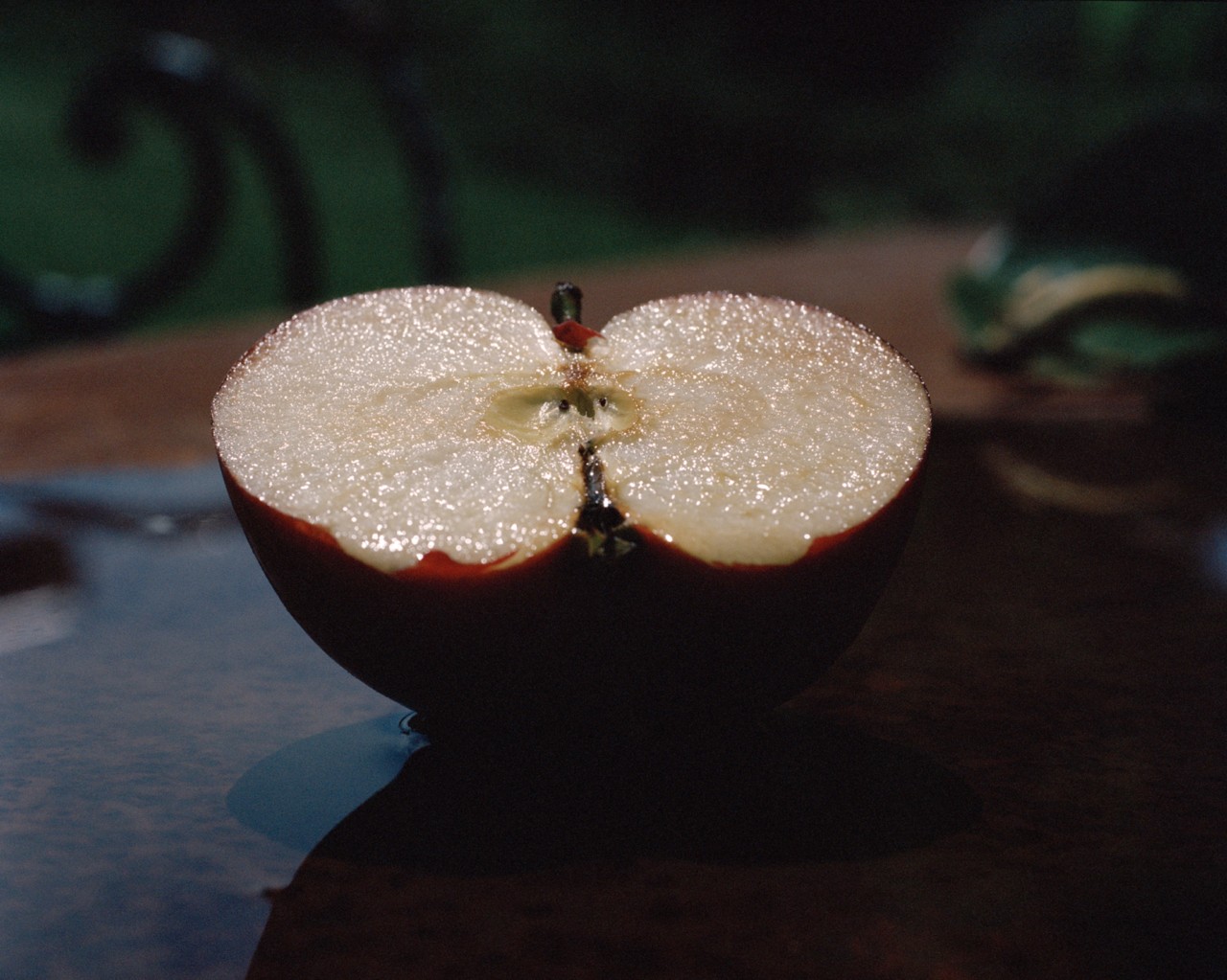 An apple cut in half is facing upwards on a black table.