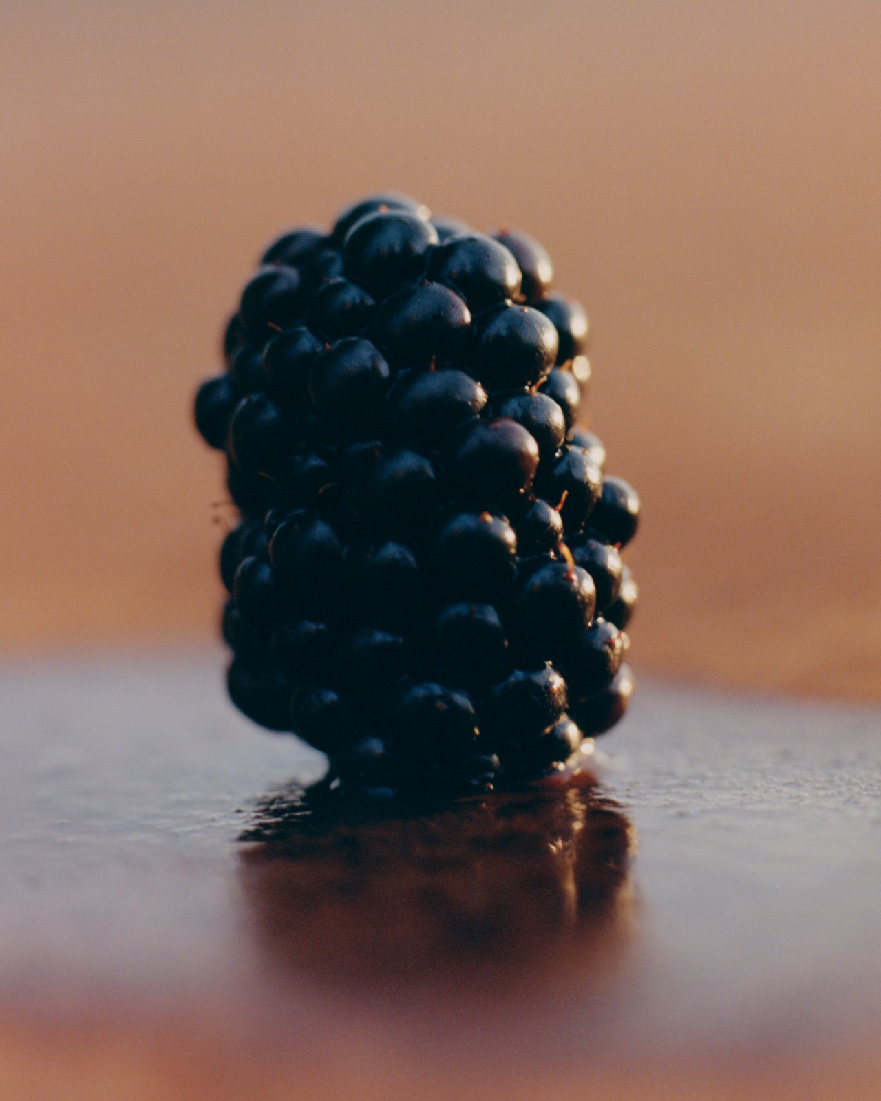 A close up of a blackberry lying on a brown table.