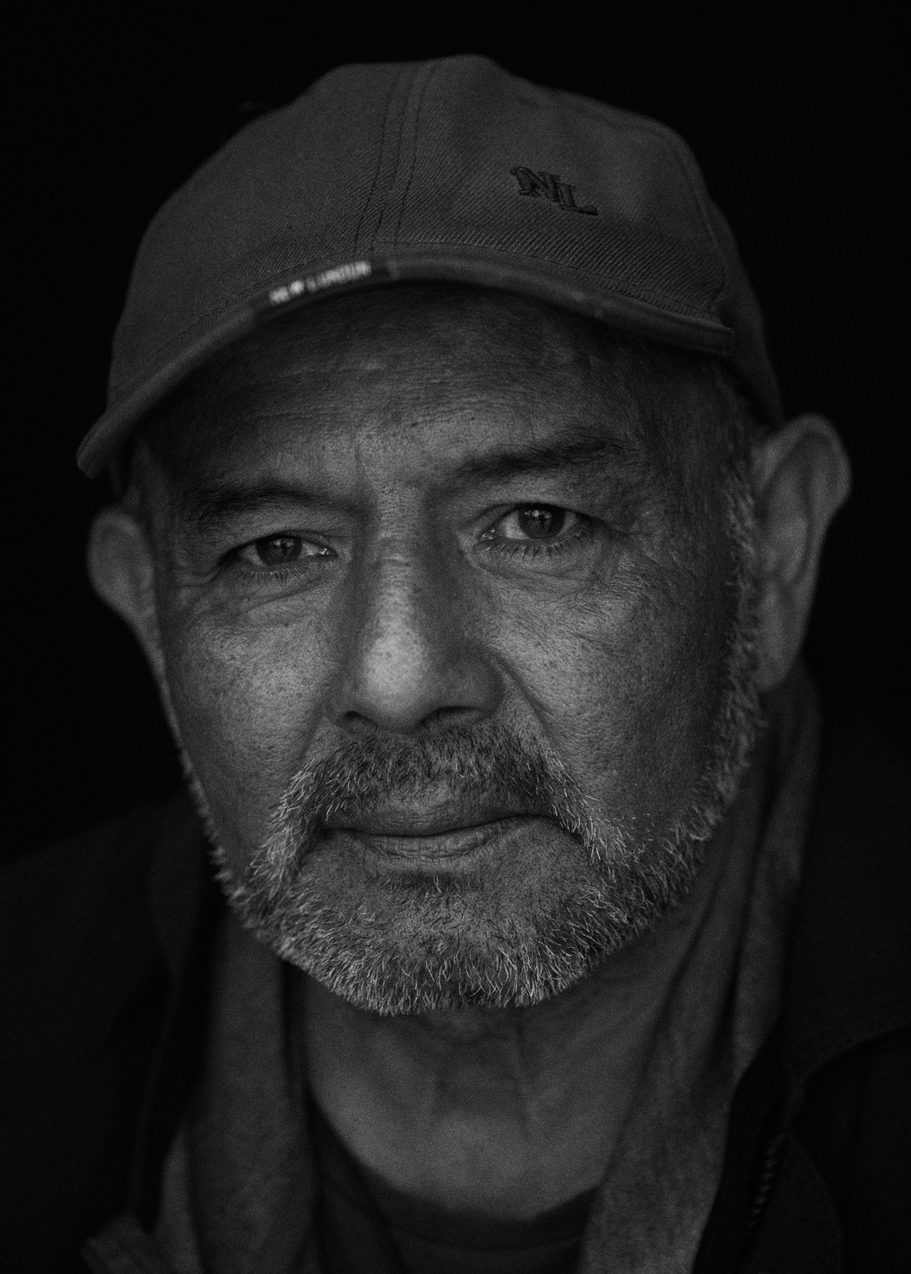 An up close portrait of a Peruvian man wearing a baseball cap.