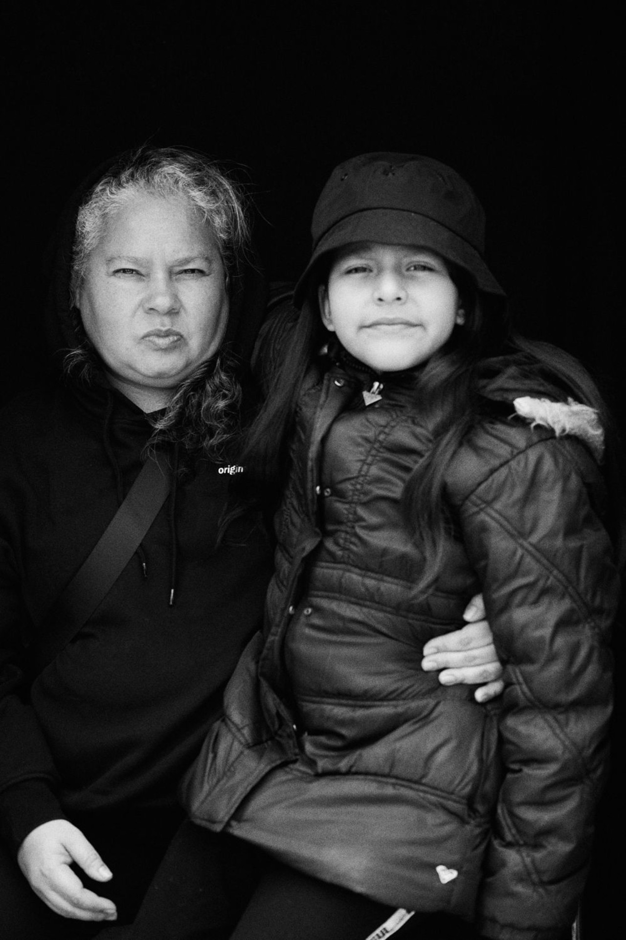 A black and white portrait of an older Peruvian woman sitting down with a young Peruvian girl sitting on her lap.