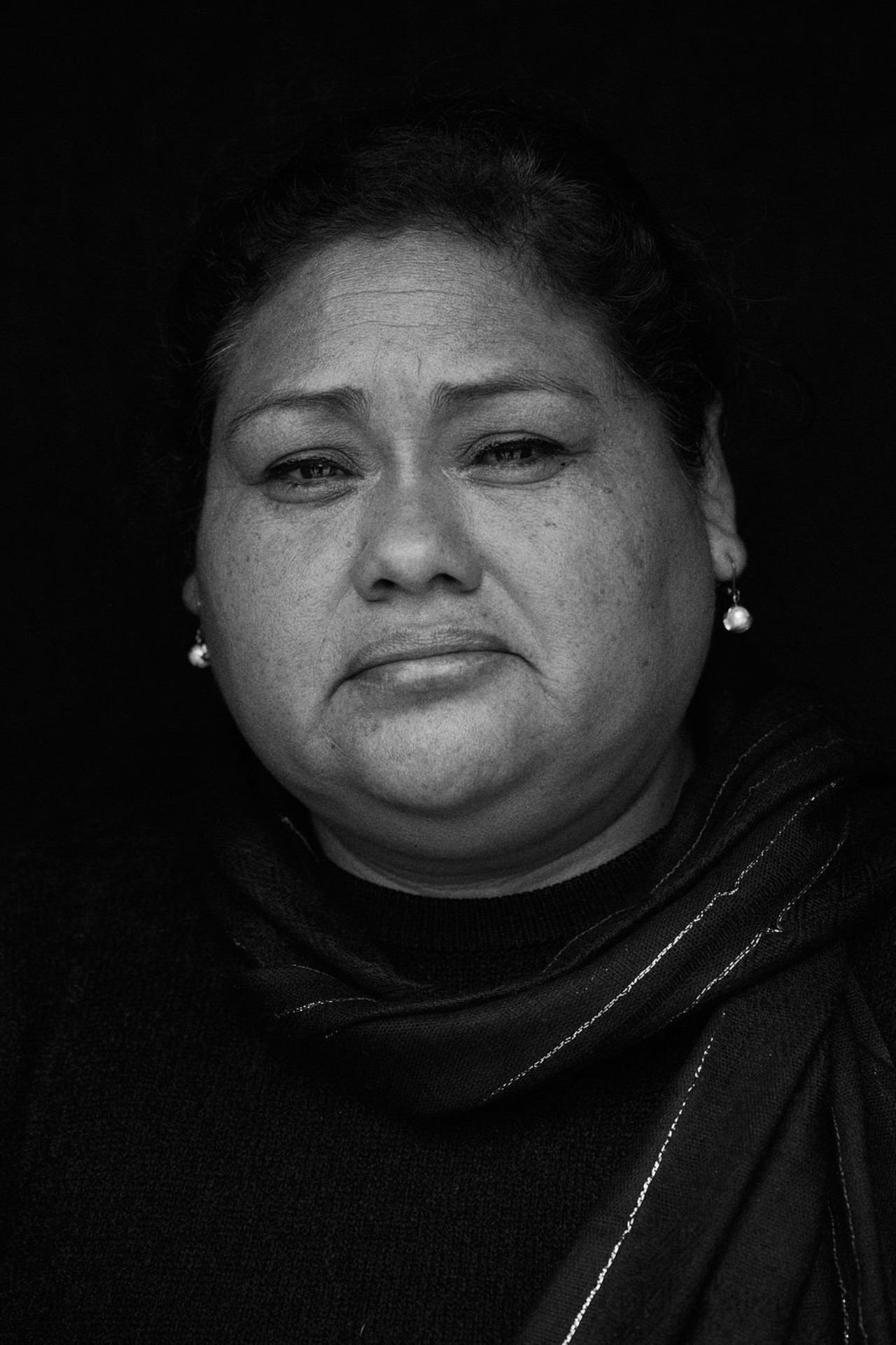 A black and white portrait of a Peruvian woman looking melancholy.