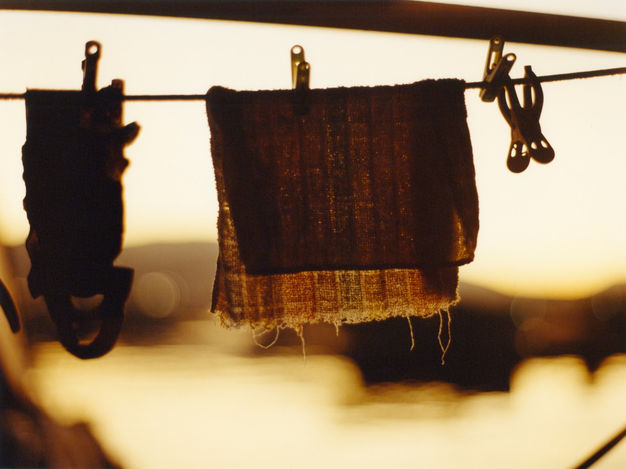 A small towel hangs on a clothesline during dusk.
