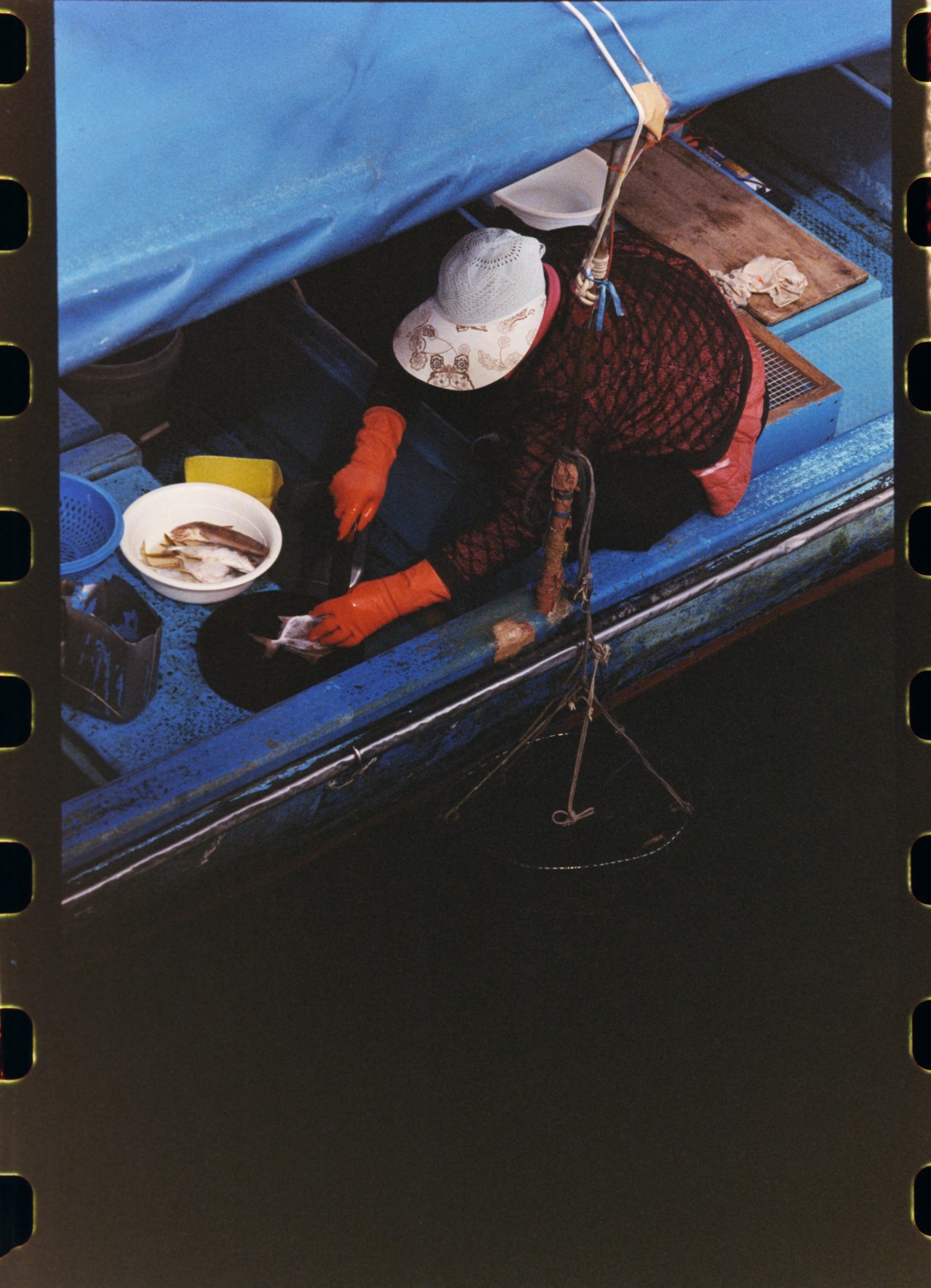 A fisher guts fish in their blue boat in a Hong King village.