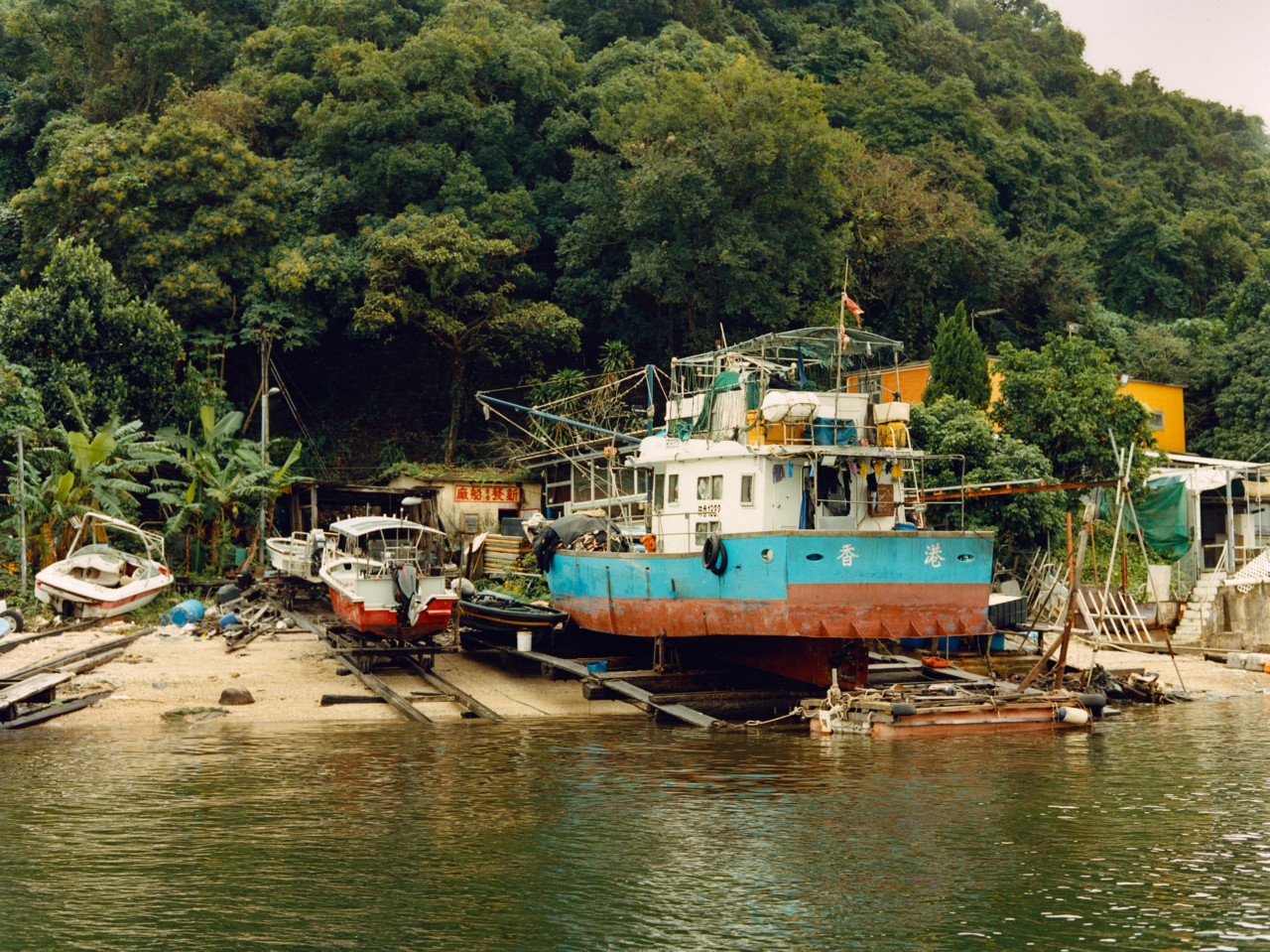 A large boat sits on the shore of a Hong Kong village.