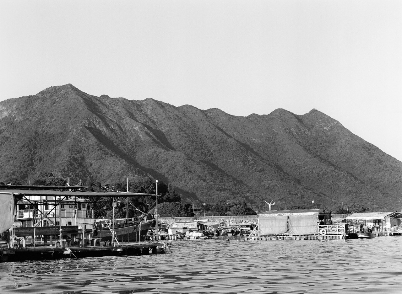 Large mountains sit behind a Hong Kong fishing village.