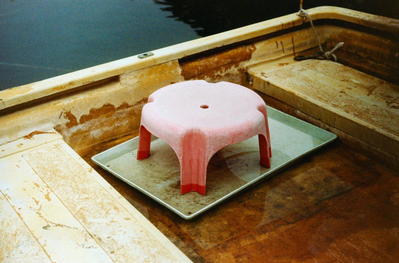 A small red stool sits inside a small brown boat.