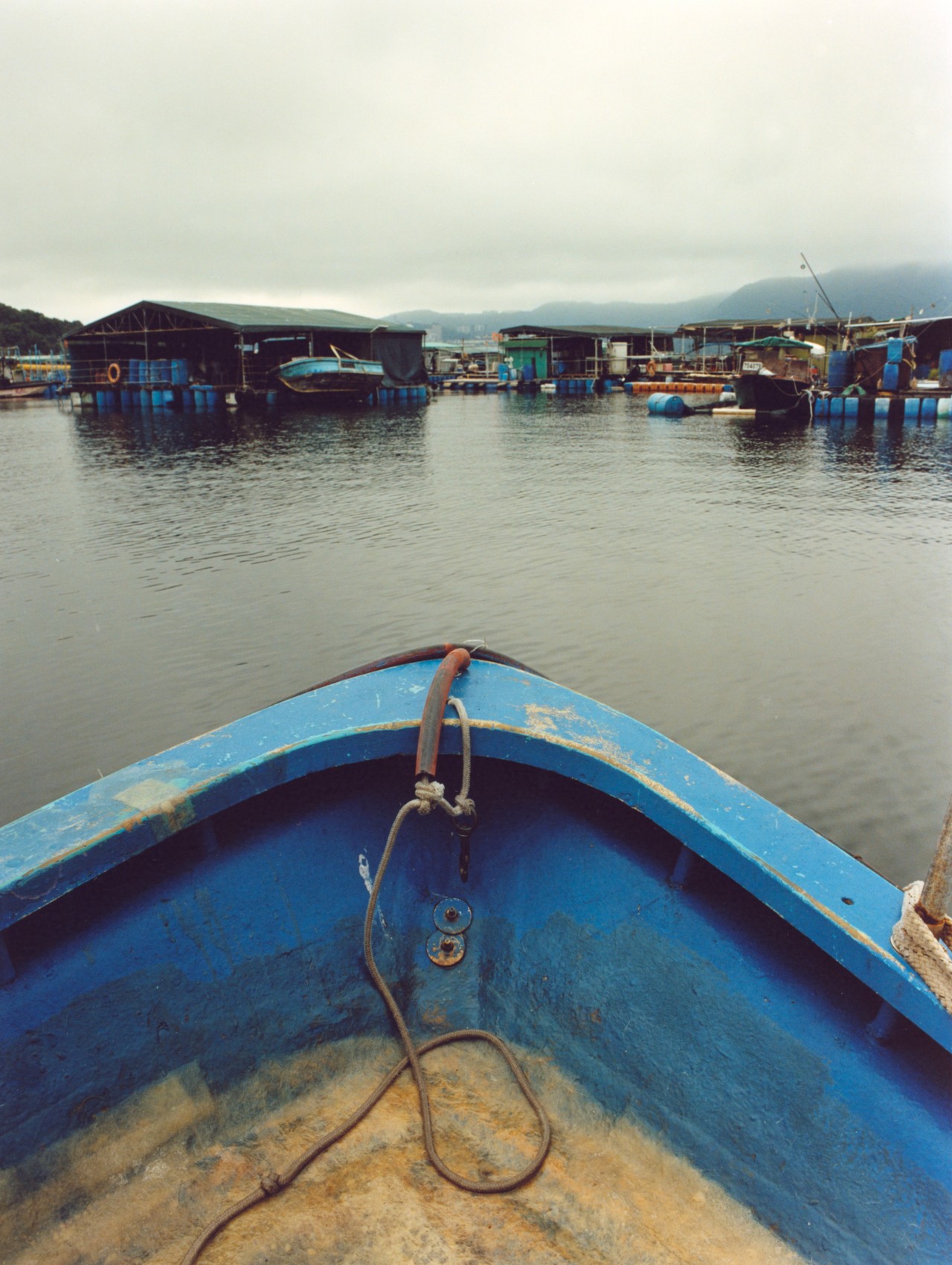 The front of a blue boat faces a fishing village in Hong Kong.