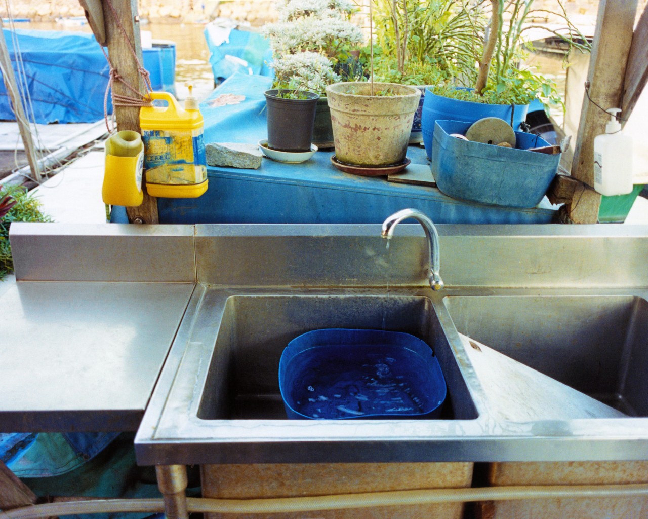 A blue bucket is filled with water inside of a sink.