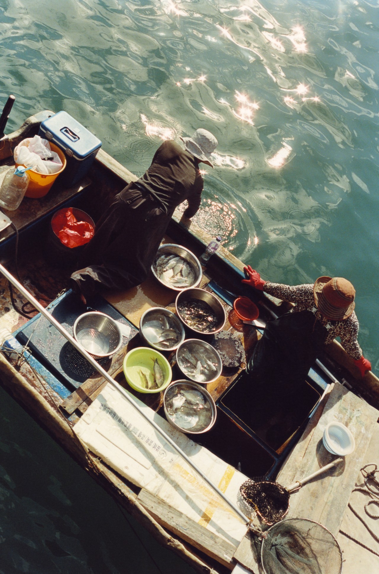Two people in a Hong Kong village peer over the side of their boat.