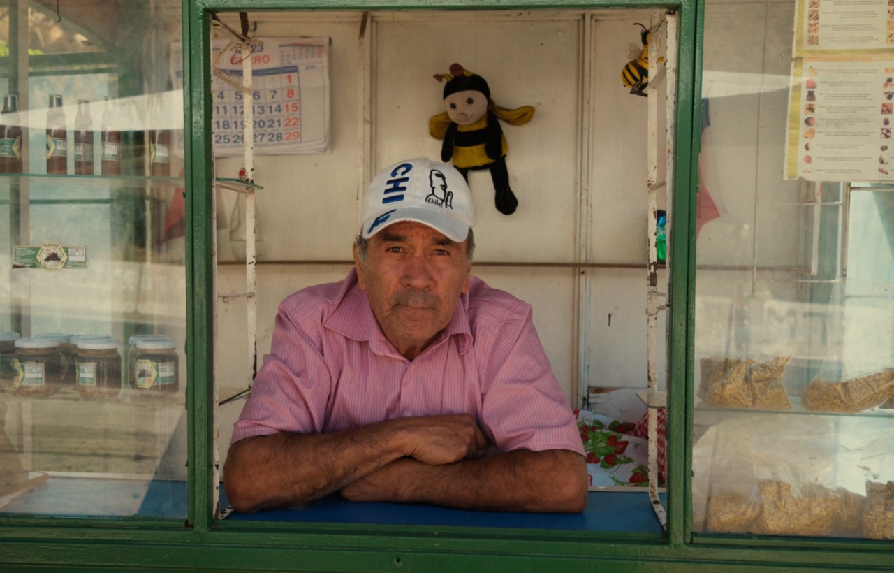 A Chilean vendor leans outside the green paned window of his store front.