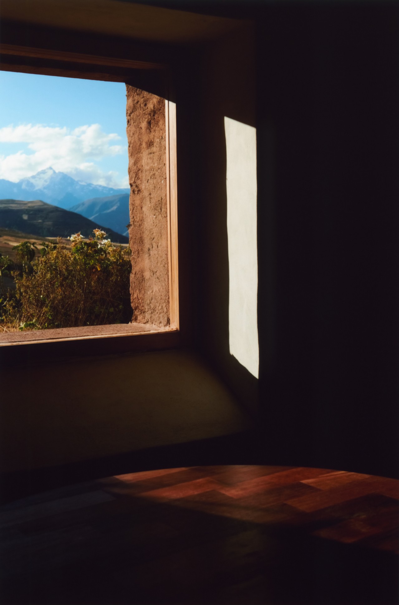 AN open window inside a home reveals the Peruvian mountains and cloudy sky.