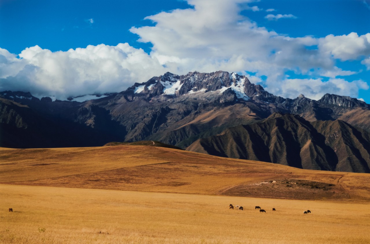 The Peruvian plains connect with the mountain range and cloudy blue sky.