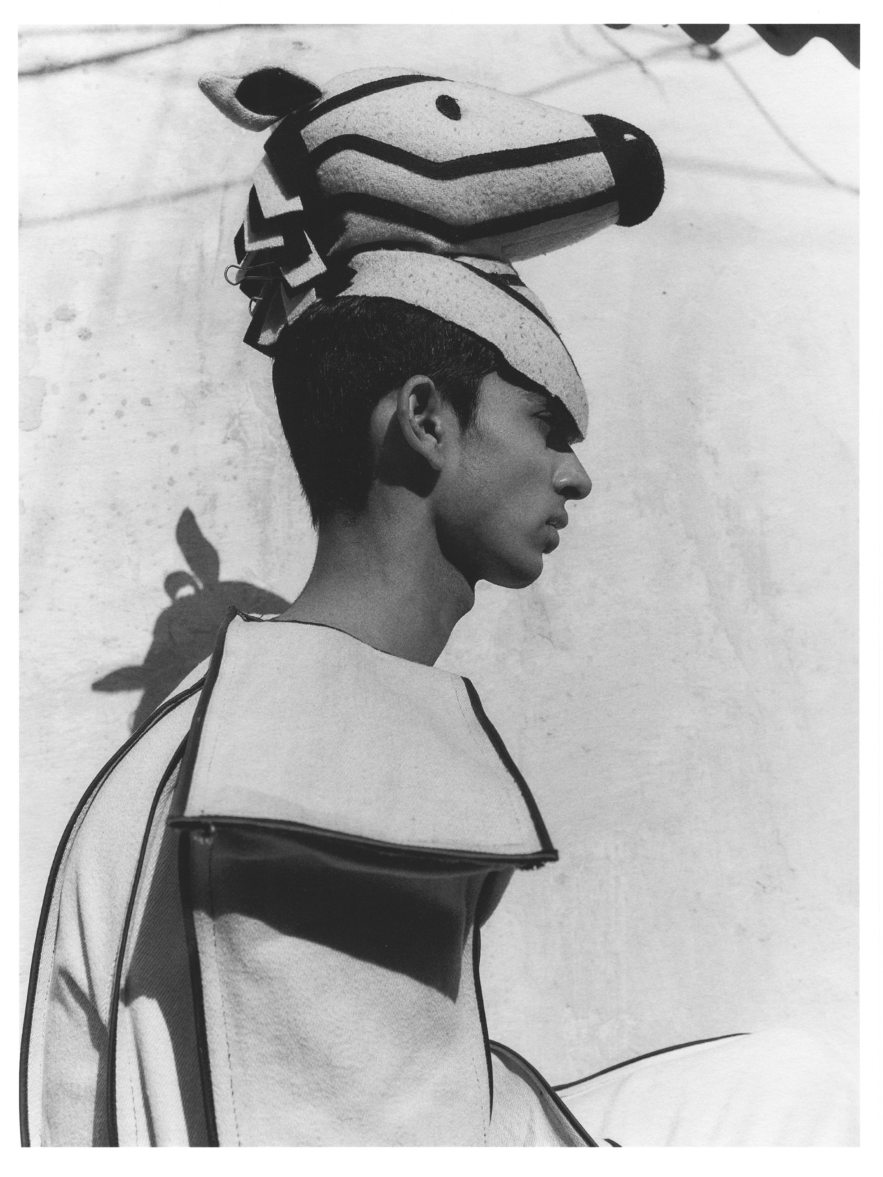 A model wearing a horse hat sits facing the side.