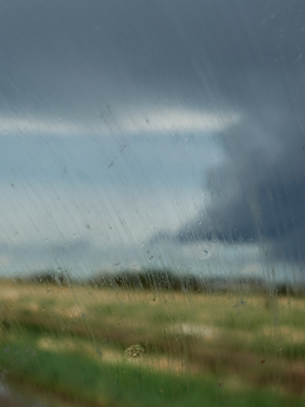 Rain falls on a car window in Clayton, NM