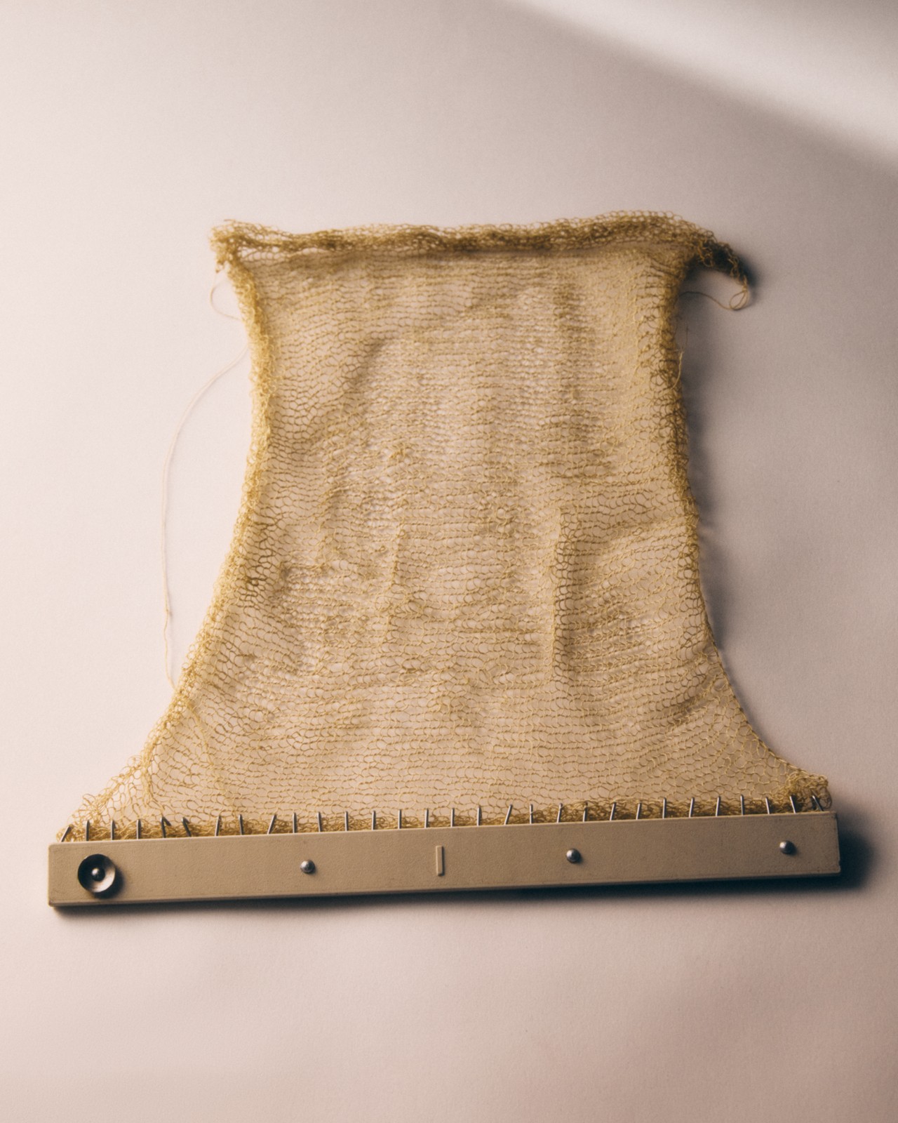 An instrument used to make wool displays a small rectangular strip of wool.