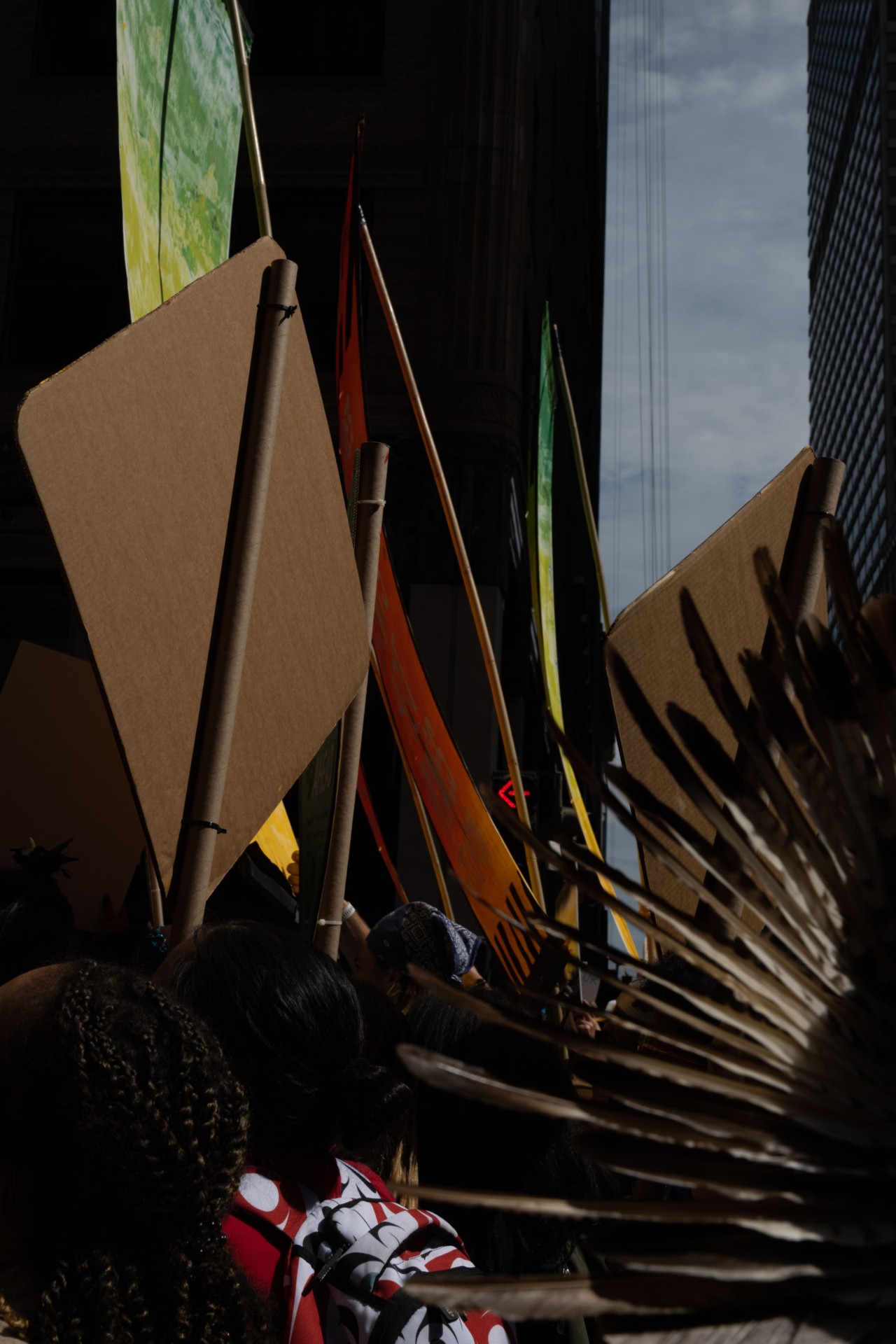 Protest signs and indigenous artifacts being raised in the air at climate change protests in NYC.