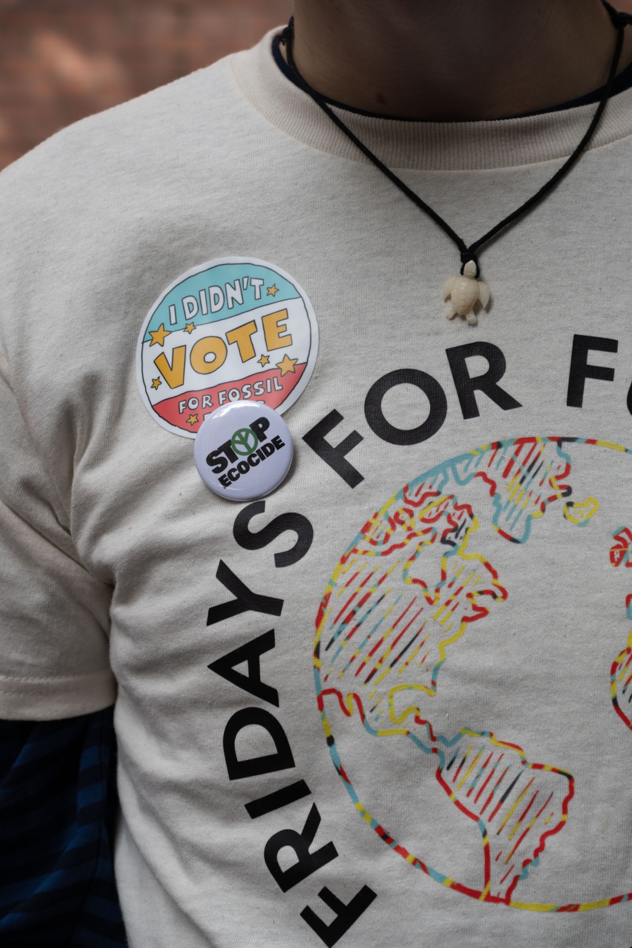 A person is wearing a t-shirt with buttons on it that call for a response to climate change.