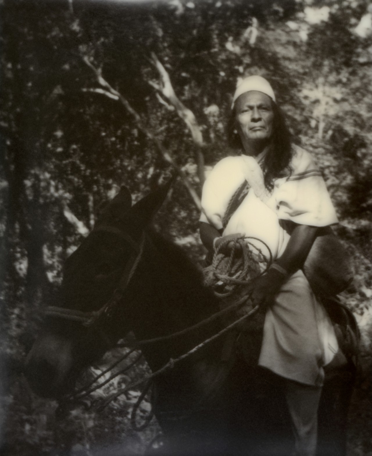 A Kogi person riding on top of a horse in the Colombian forest.