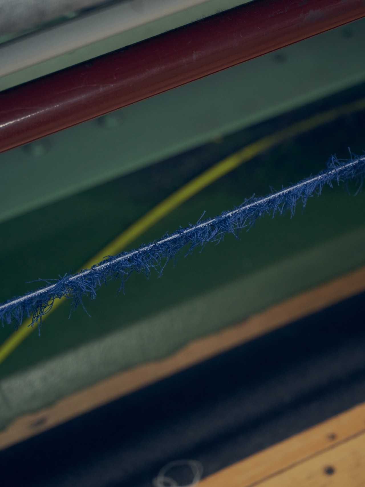 A string of freyed blue fabric hangs above a green and red metal beam.