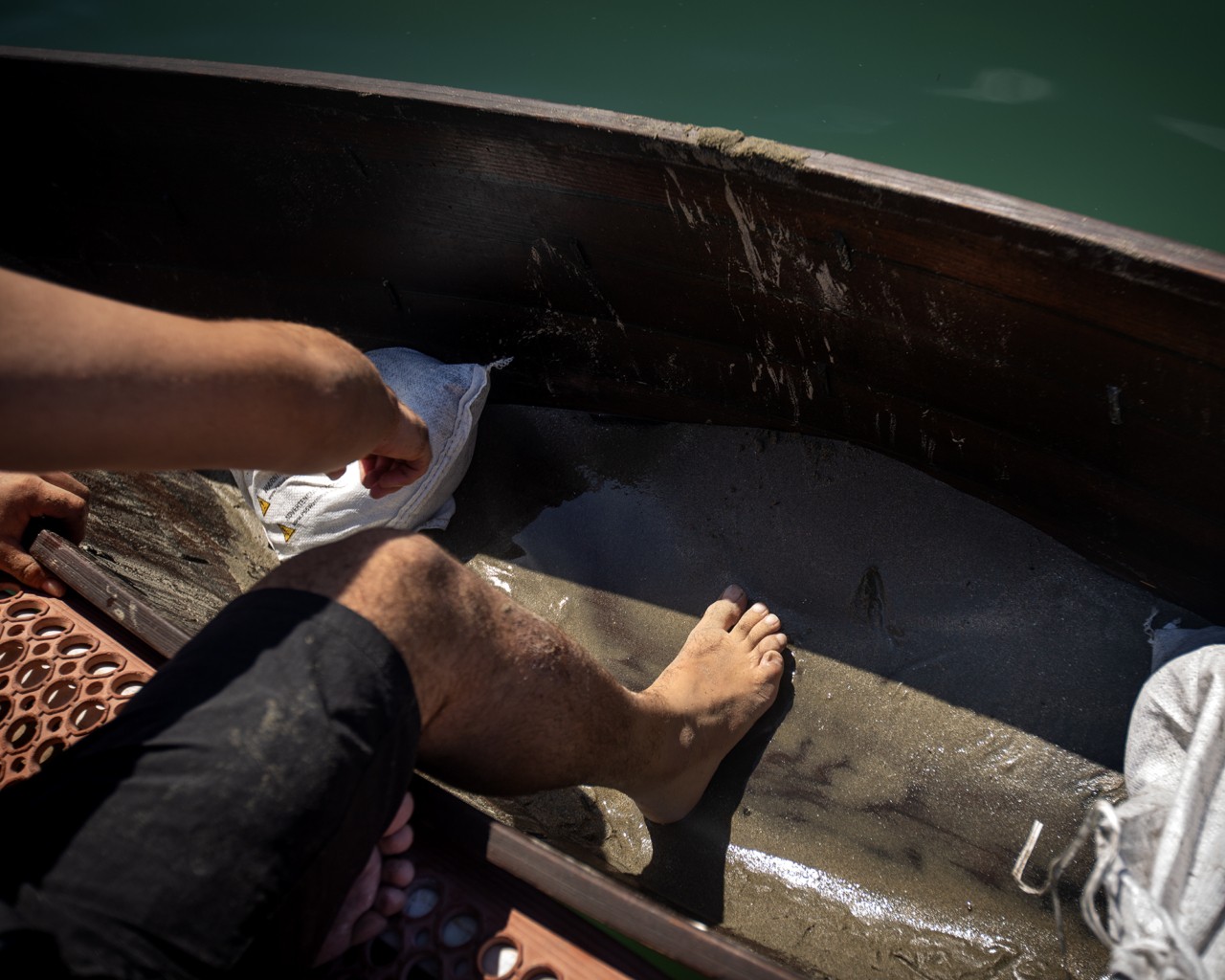 A person's foot and leg is shown crouching inside a canoe that is floating in the water.