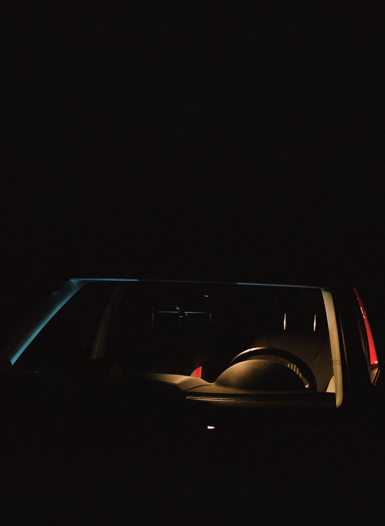 A dimly lit car sits in the shadows.
