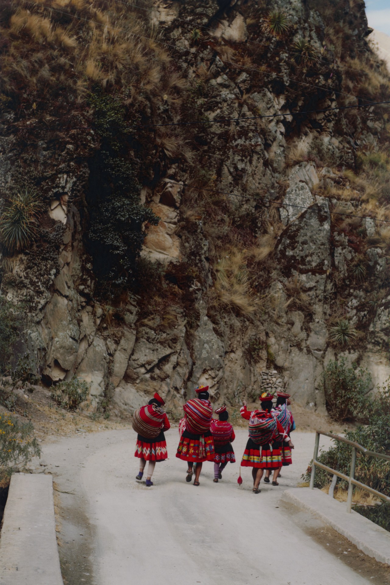 A group of Peruvian people walk down a steep road