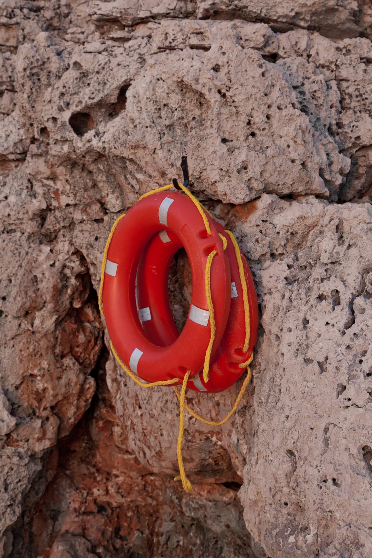 Two orange safety ring buoys hang on rocky cliff in Turkey