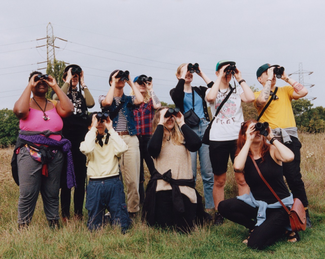 A group of people all look in the same direction with their binoculars.