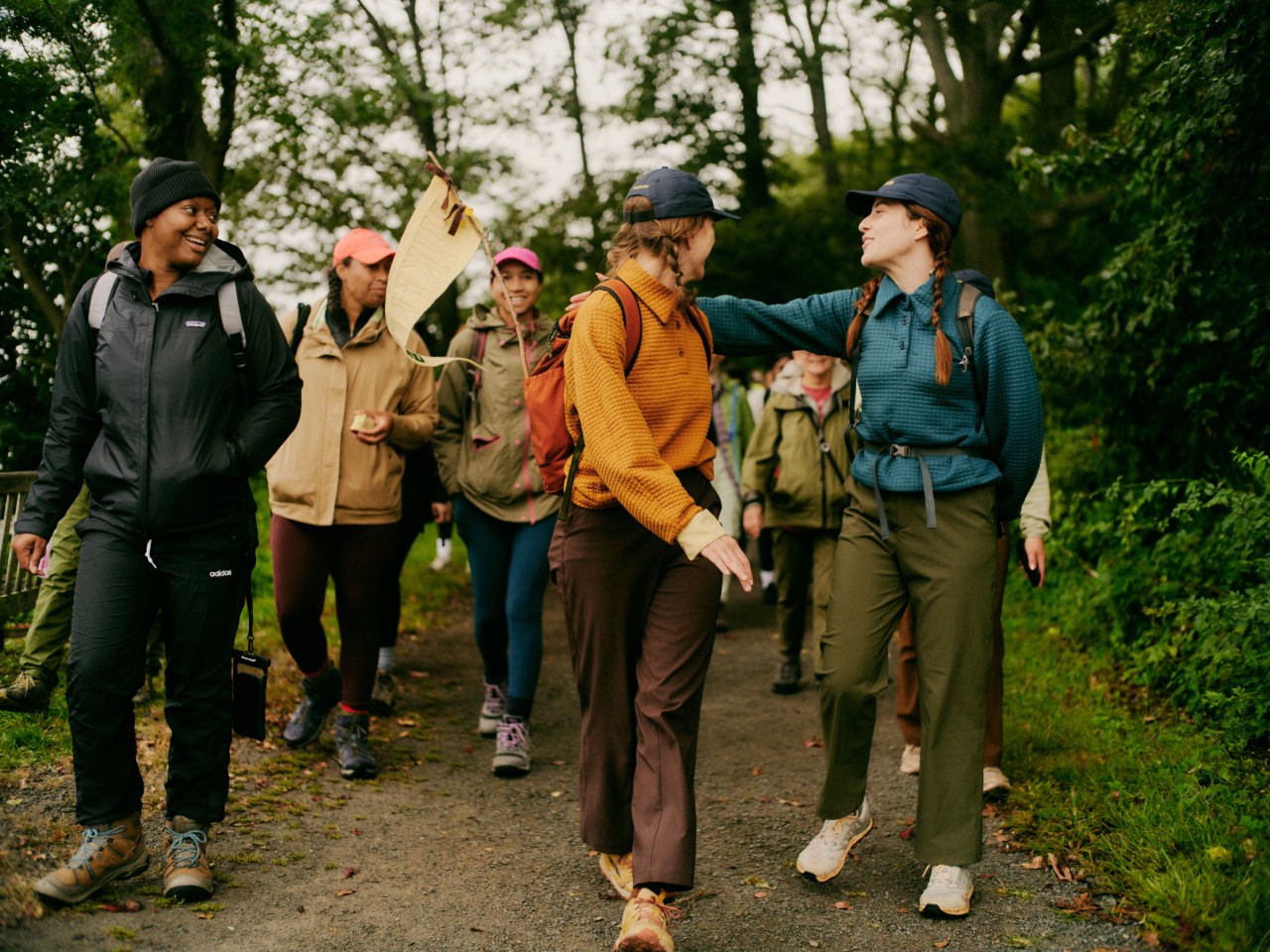 Several individuals dressed in hiking gear walking on a path in the forest.
