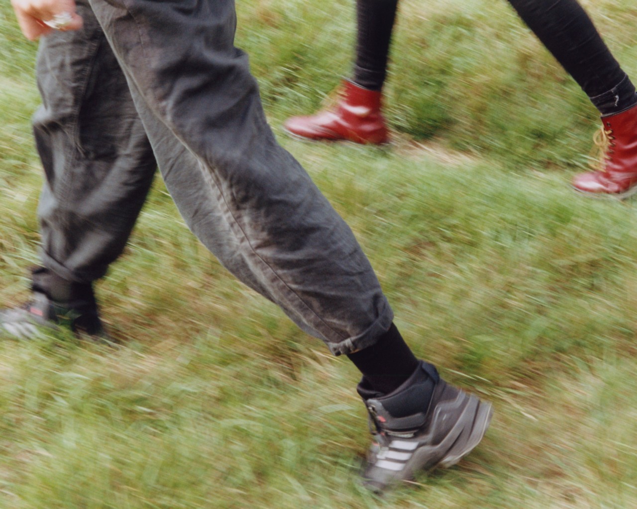 The legs of two people are shown walking in the grass.