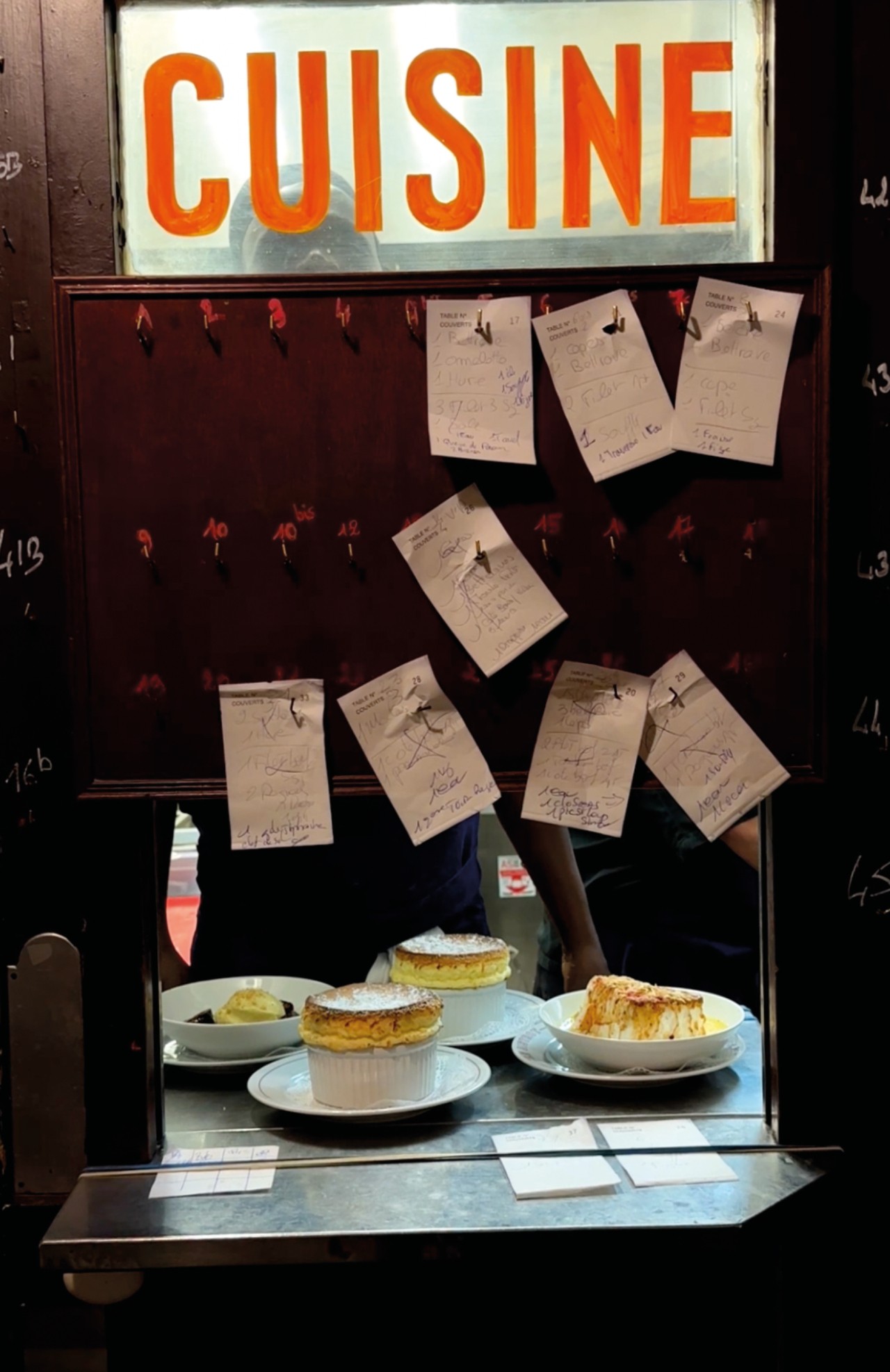 Four plates of dessert sit on a counter top in a restaurant.