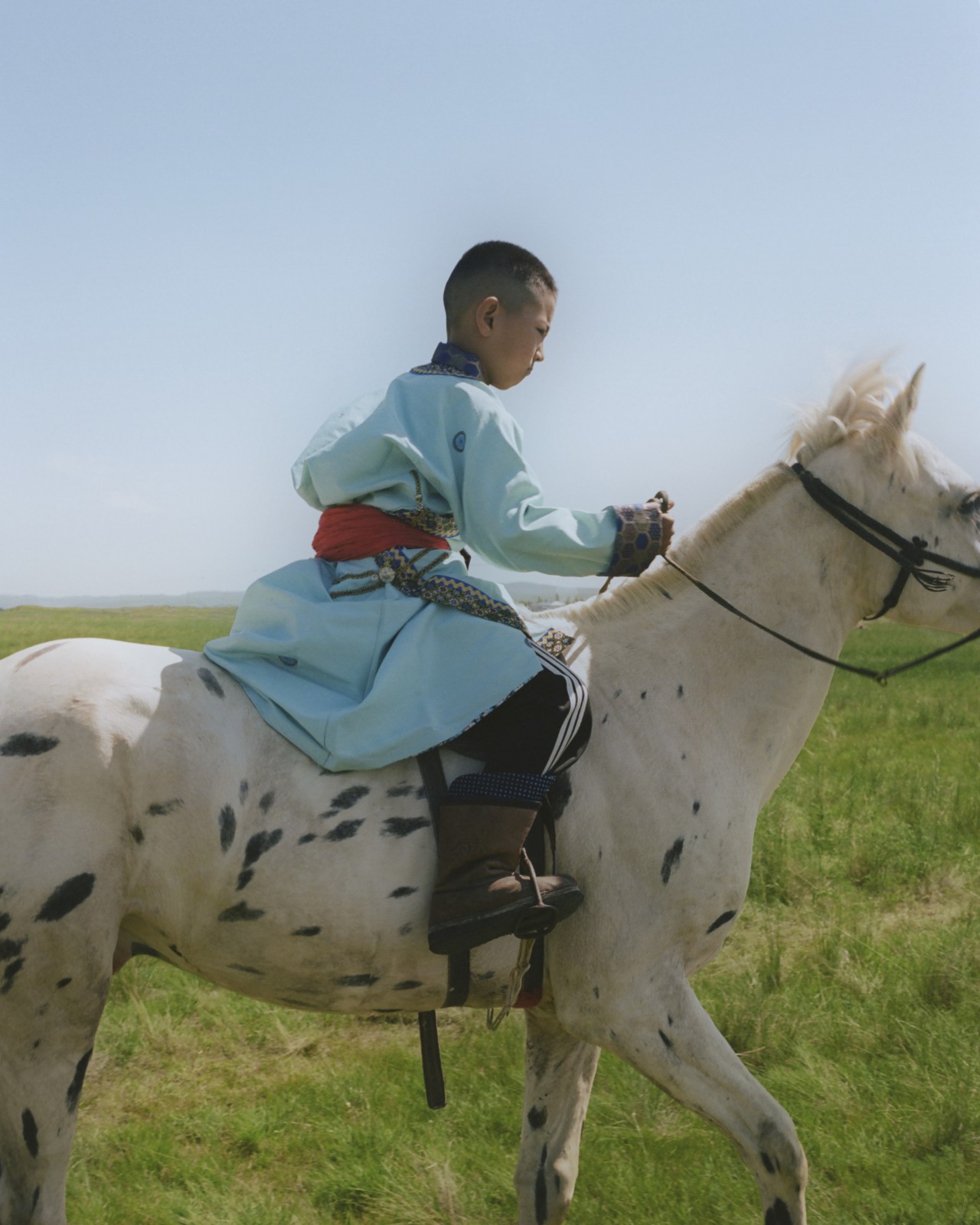 A Mongolian child rides their horse.