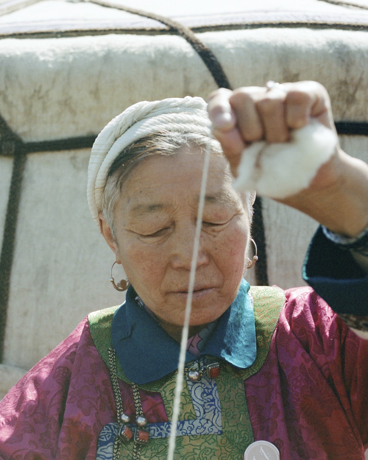 A Mongolian woman pulls on a piece of string.