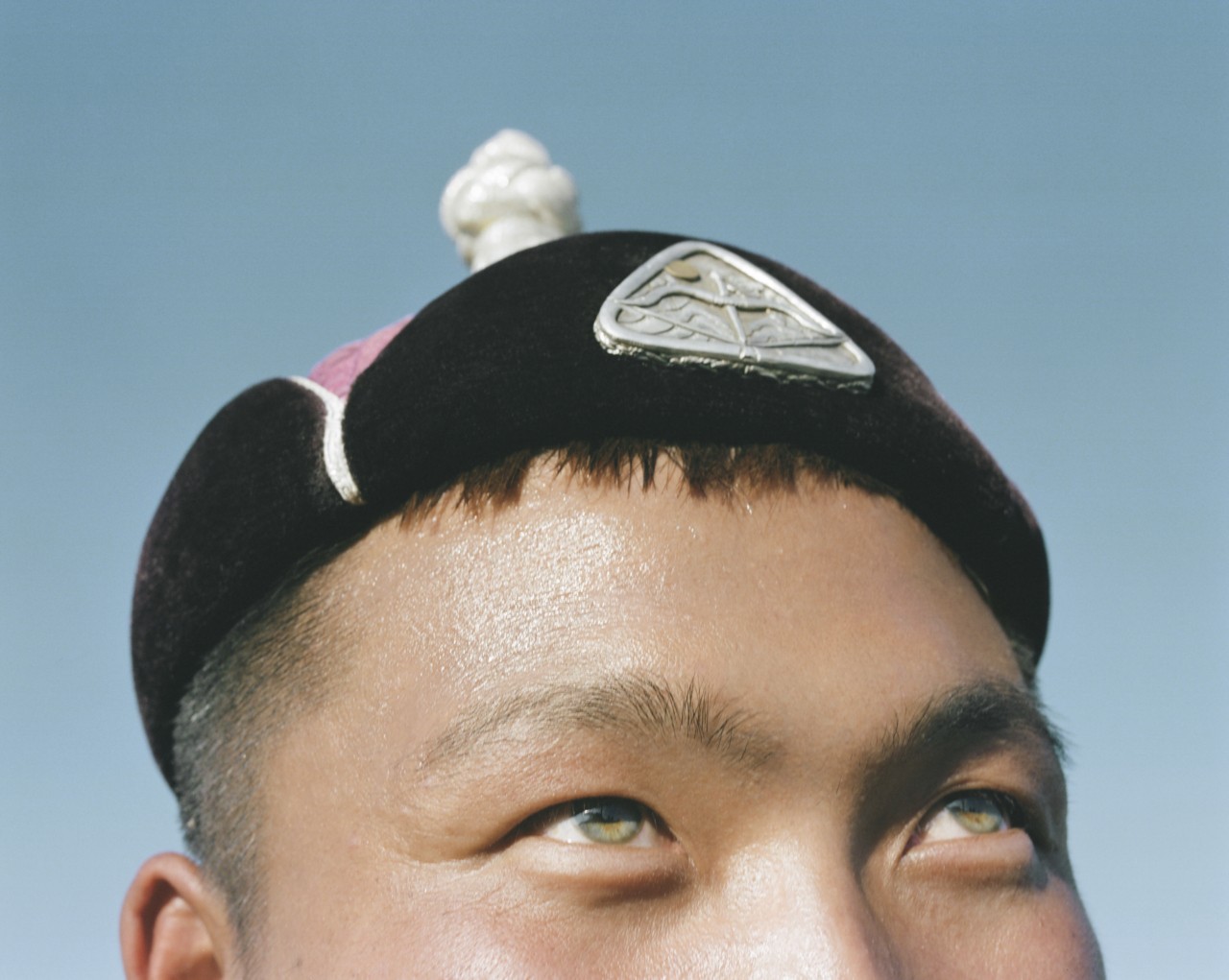 A close up of the top half of a Mongolian person's face, eyes looking up toward the sky.
