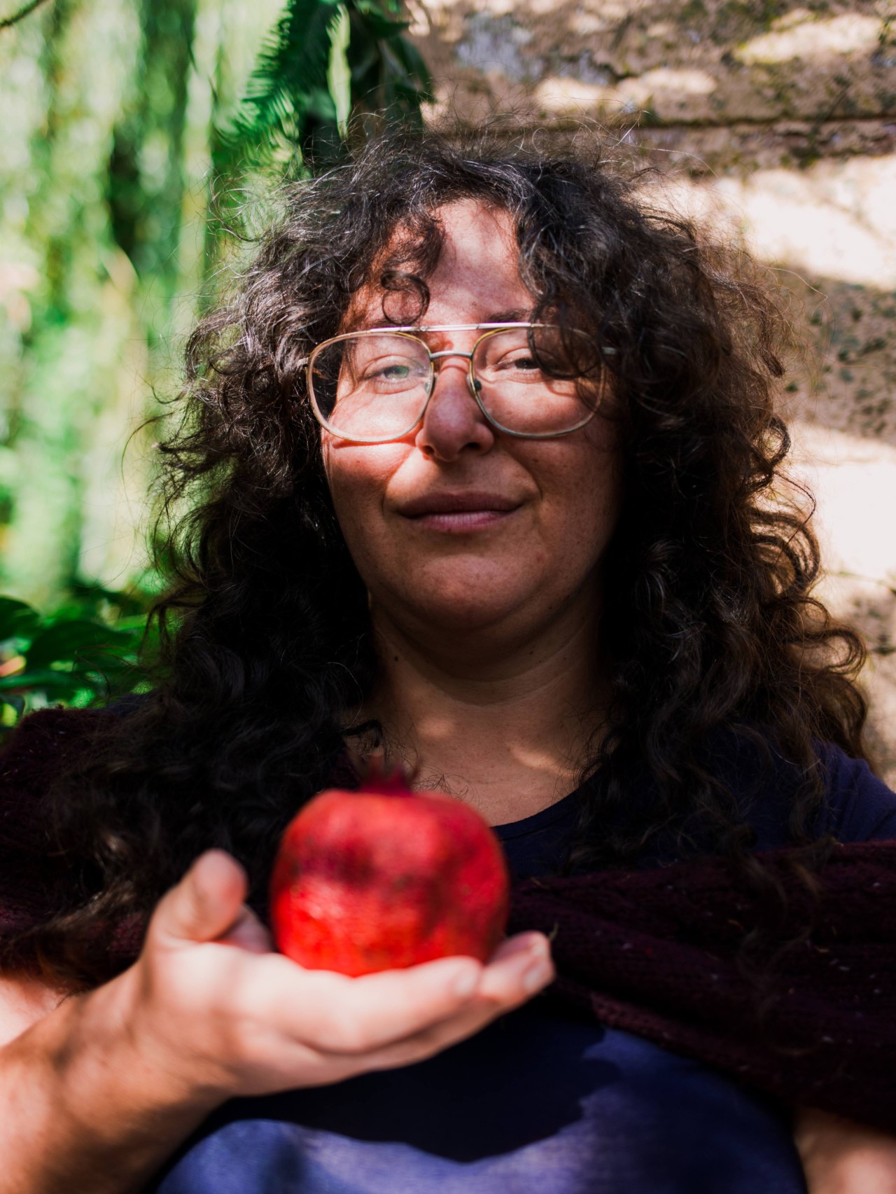 A person holds an apple while looking into the camera.