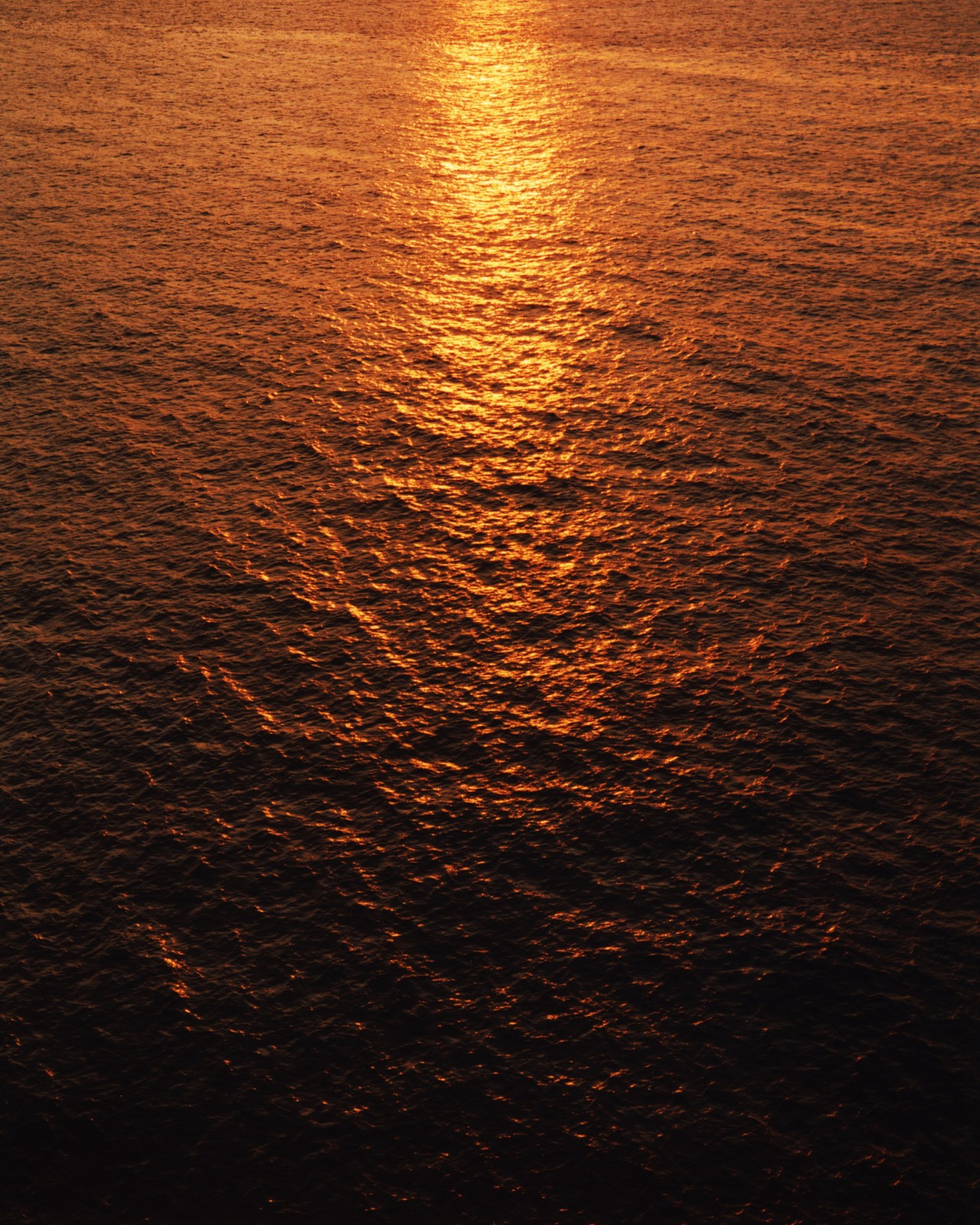 The sunset reflects on the ocean surface.