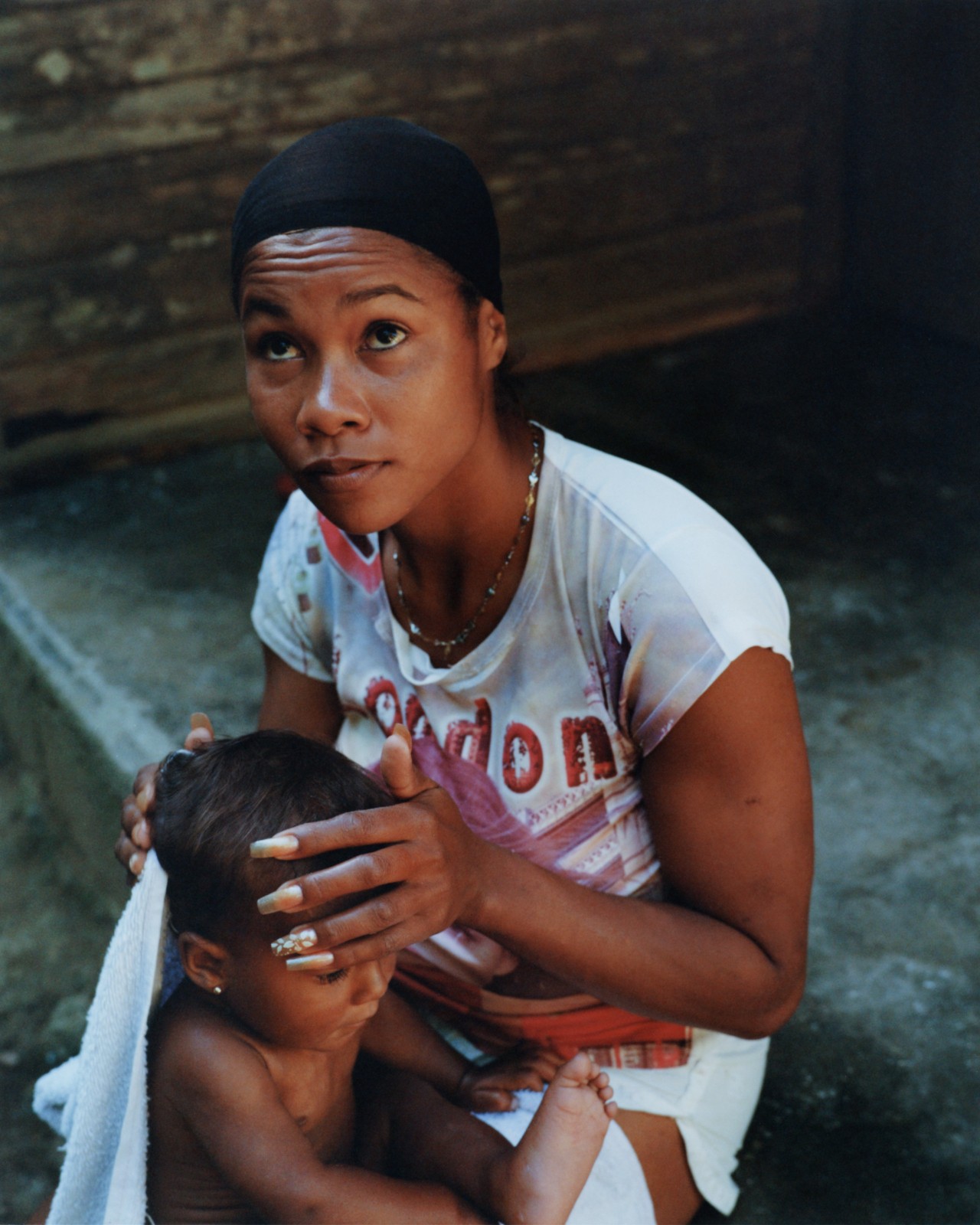 A woman holds a baby in her lap while looking up.