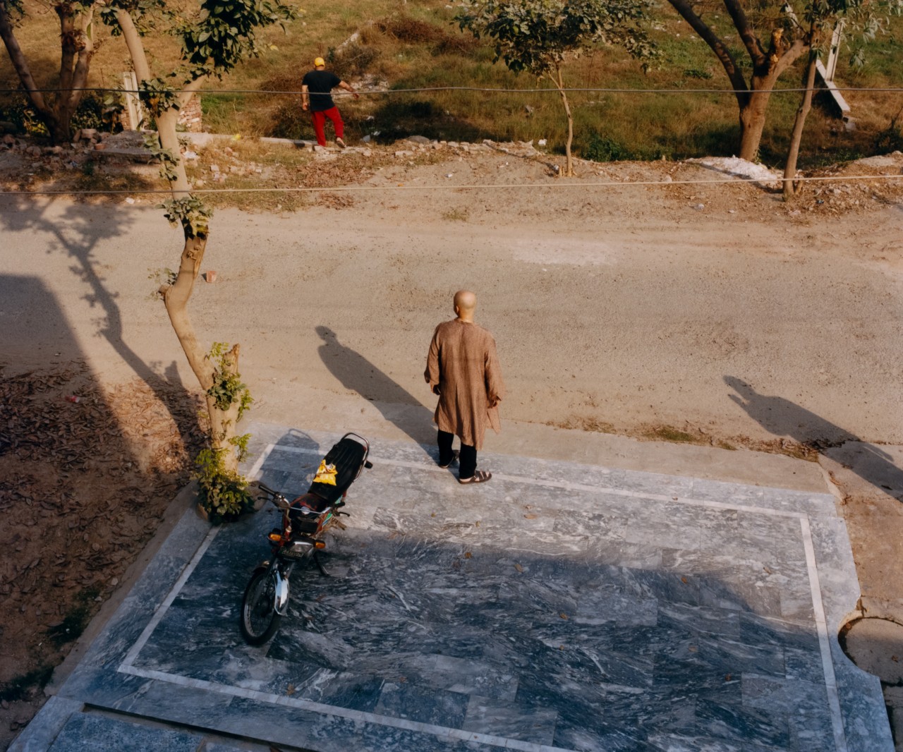 A persons stands on a dirt street.