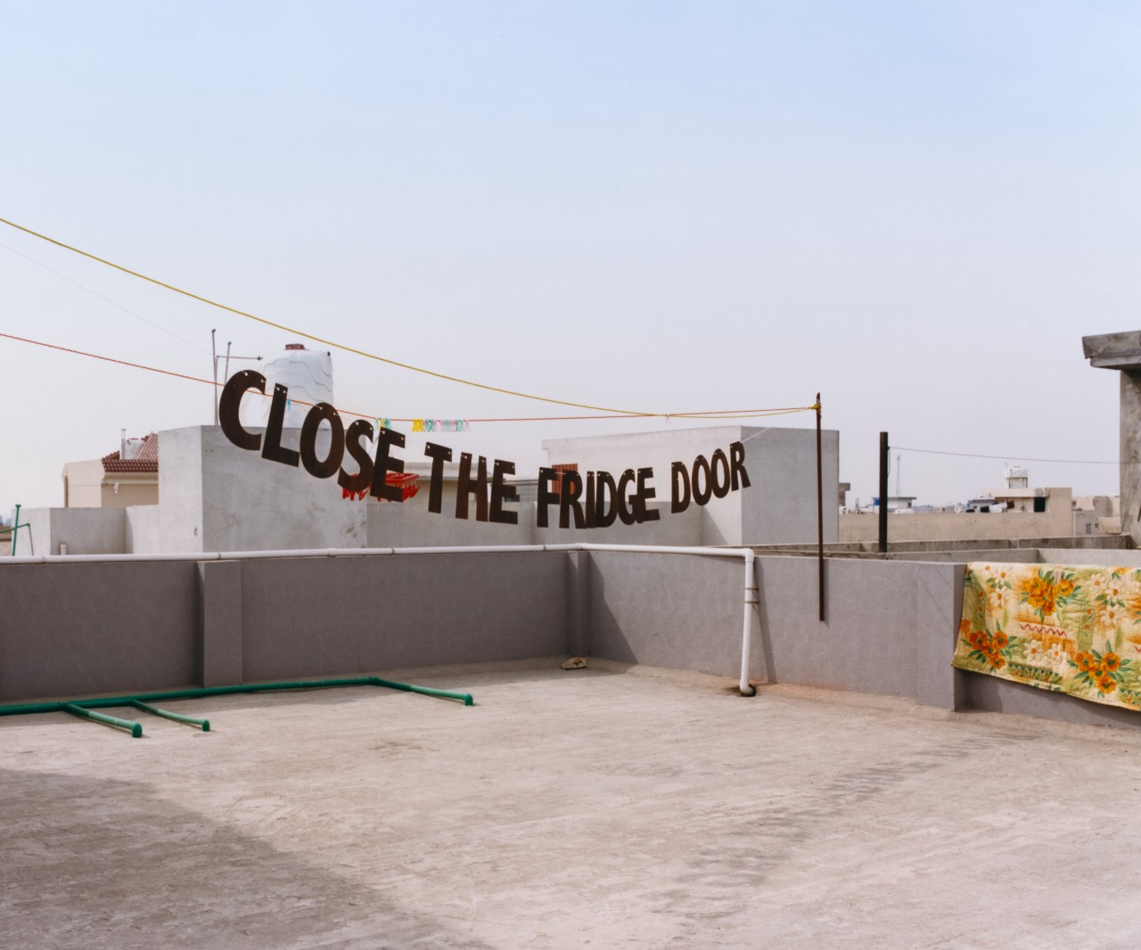 A sign hangs along a line on the roof of a building.