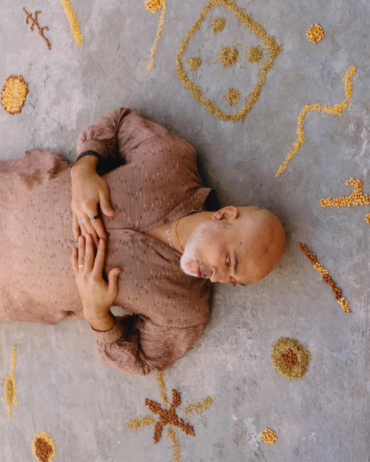 A person lays sideways on a concrete floor with designs surrounding them.