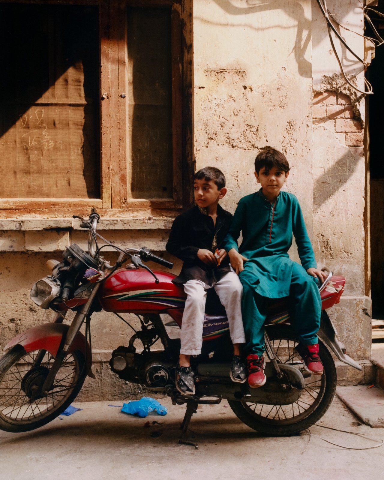 Two children sit on a motorcycle in the street.
